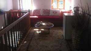 Uma sala de estar acolhedora com um sofá vermelho, uma mesa de centro de madeira e uma escada.