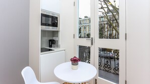 A compact kitchen with a microwave, a coffee machine, and a small table with a potted plant. - Inverness Terrace Serviced Apartments by Concept Apartments (London)
