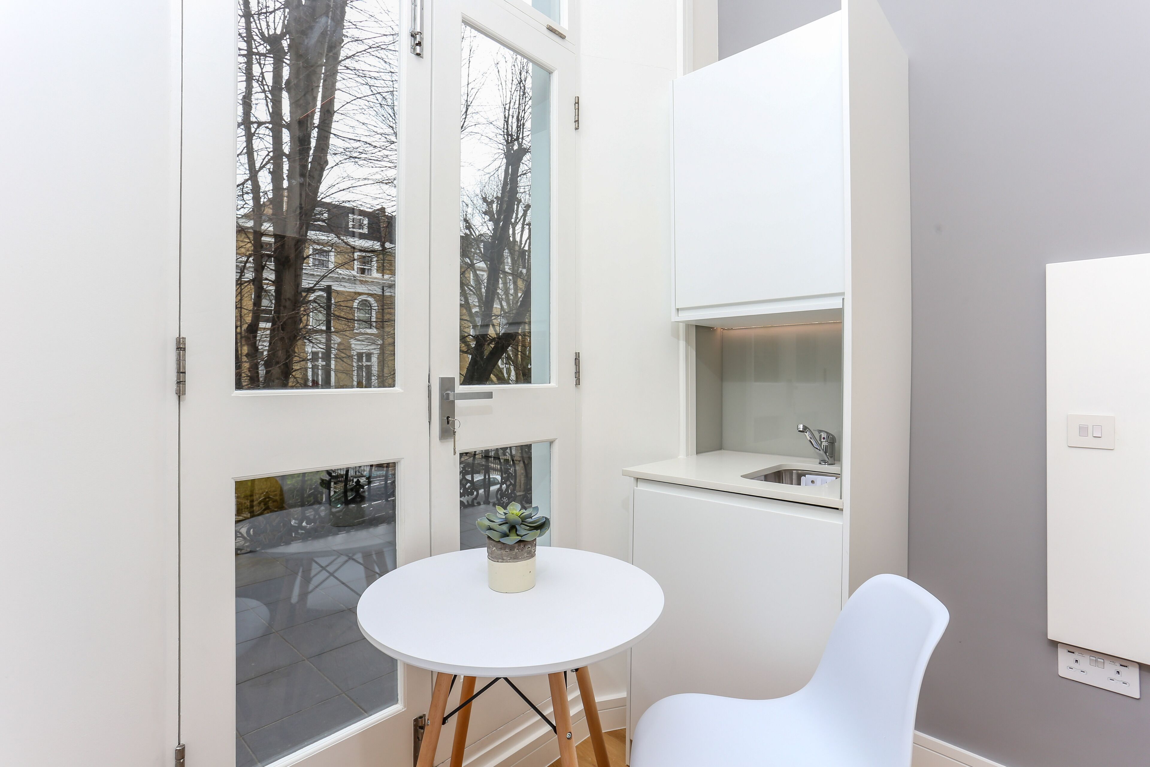 A compact kitchen with a white countertop, a sink, and a small potted plant.
