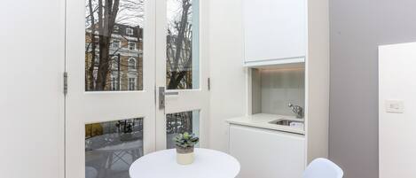 A compact kitchen with a white countertop, a sink, and a small potted plant.
