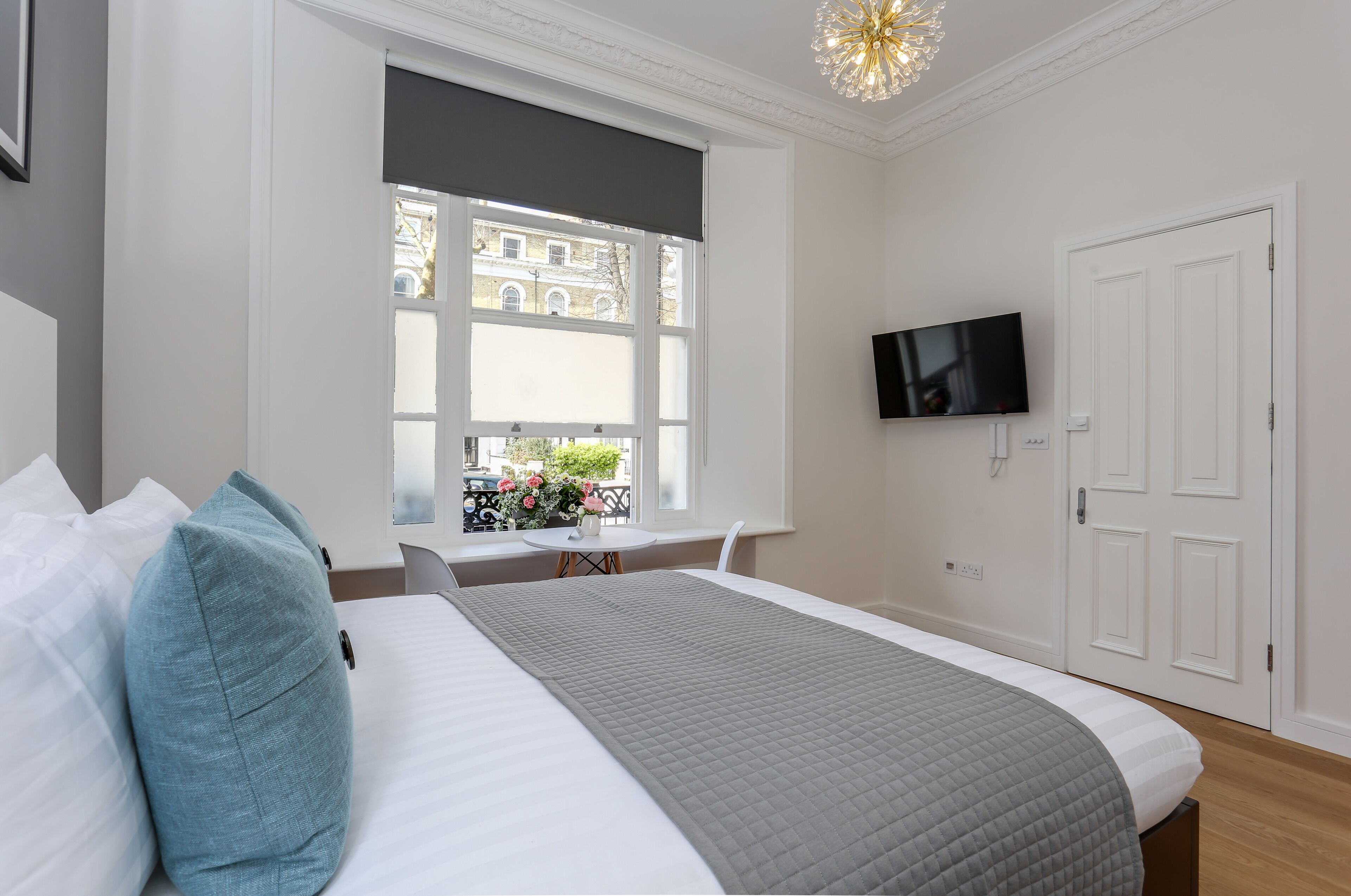 A bedroom with a bed, a TV, a window, and a door.
