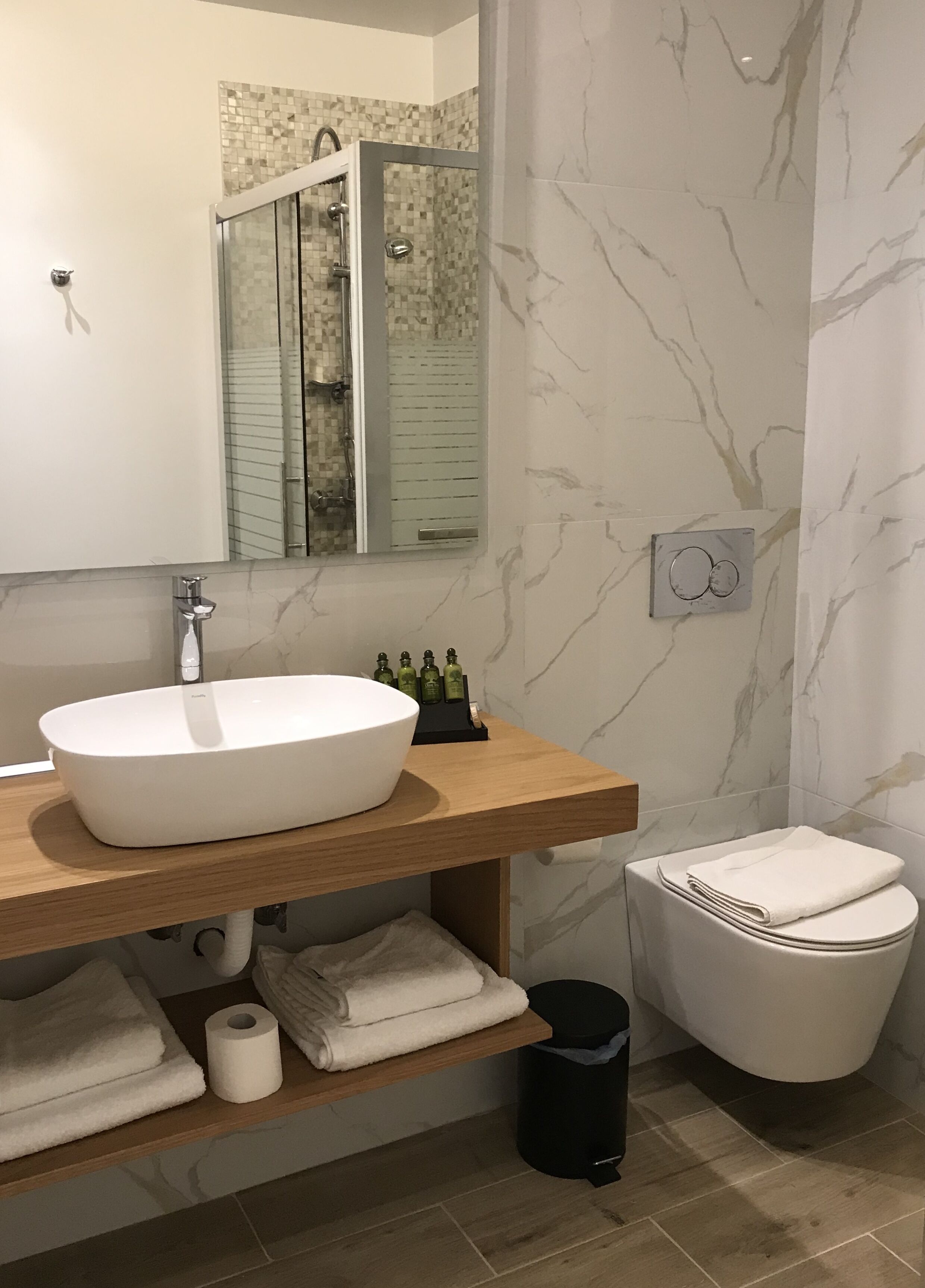 Une salle de bain moderne avec un grand lavabo blanc, un miroir, une douche en verre et des toilettes.