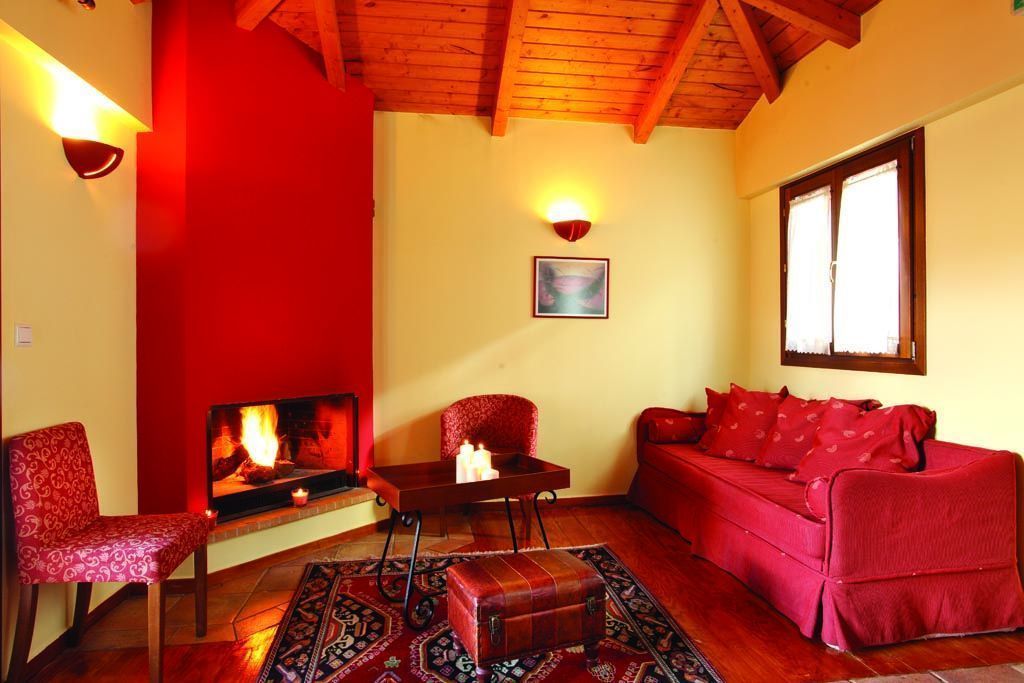 Una sala de estar con chimenea, muebles rojos y una alfombra estampada.