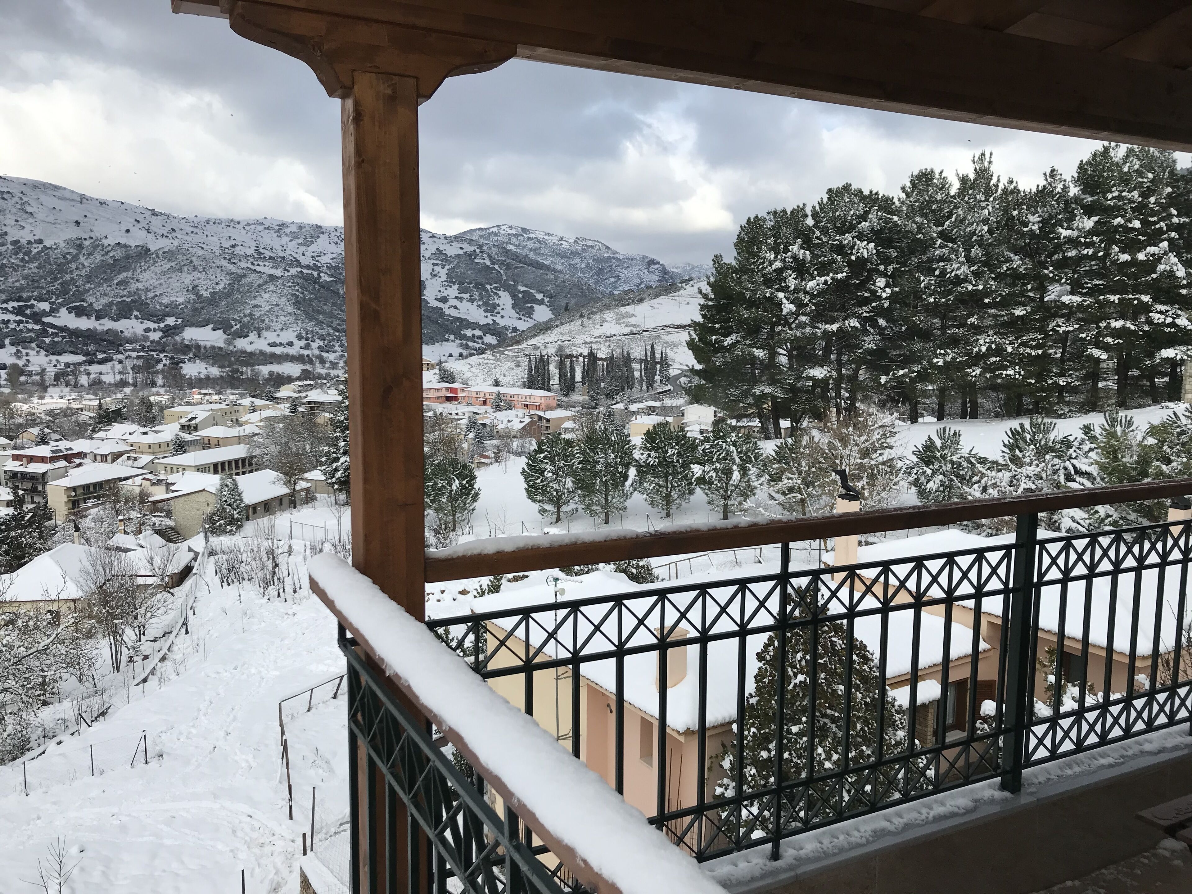 A snowy mountain view from a balcony with a metal railing.