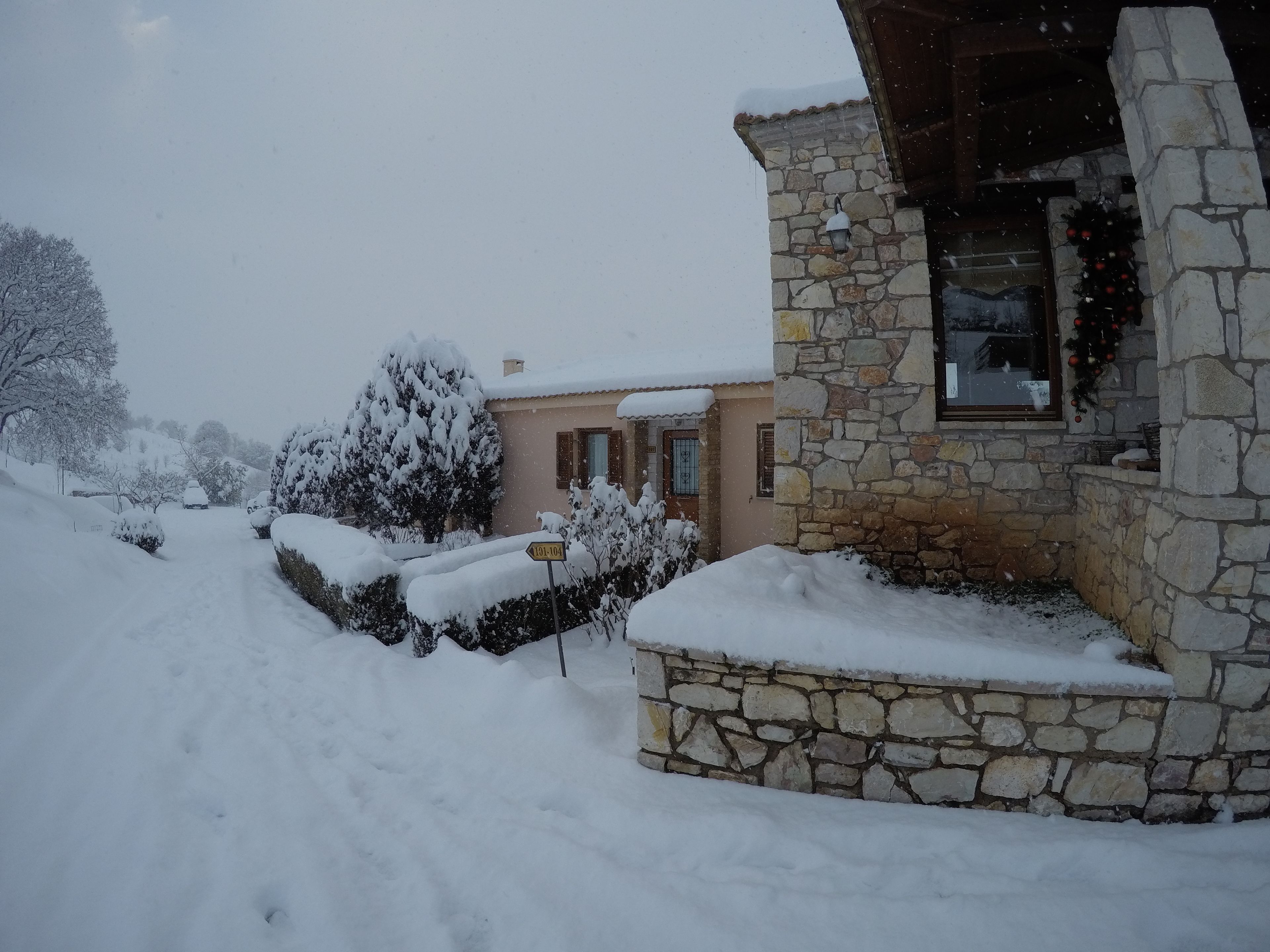 A stone building with a snow-covered entrance and a visible road sign.
