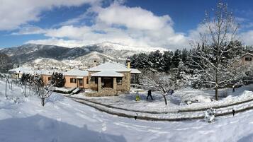 Un pueblo cubierto de nieve con edificios de piedra, cielo despejado y montañas nevadas al fondo.