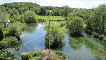 A river with surrounding greenery and a stone wall.