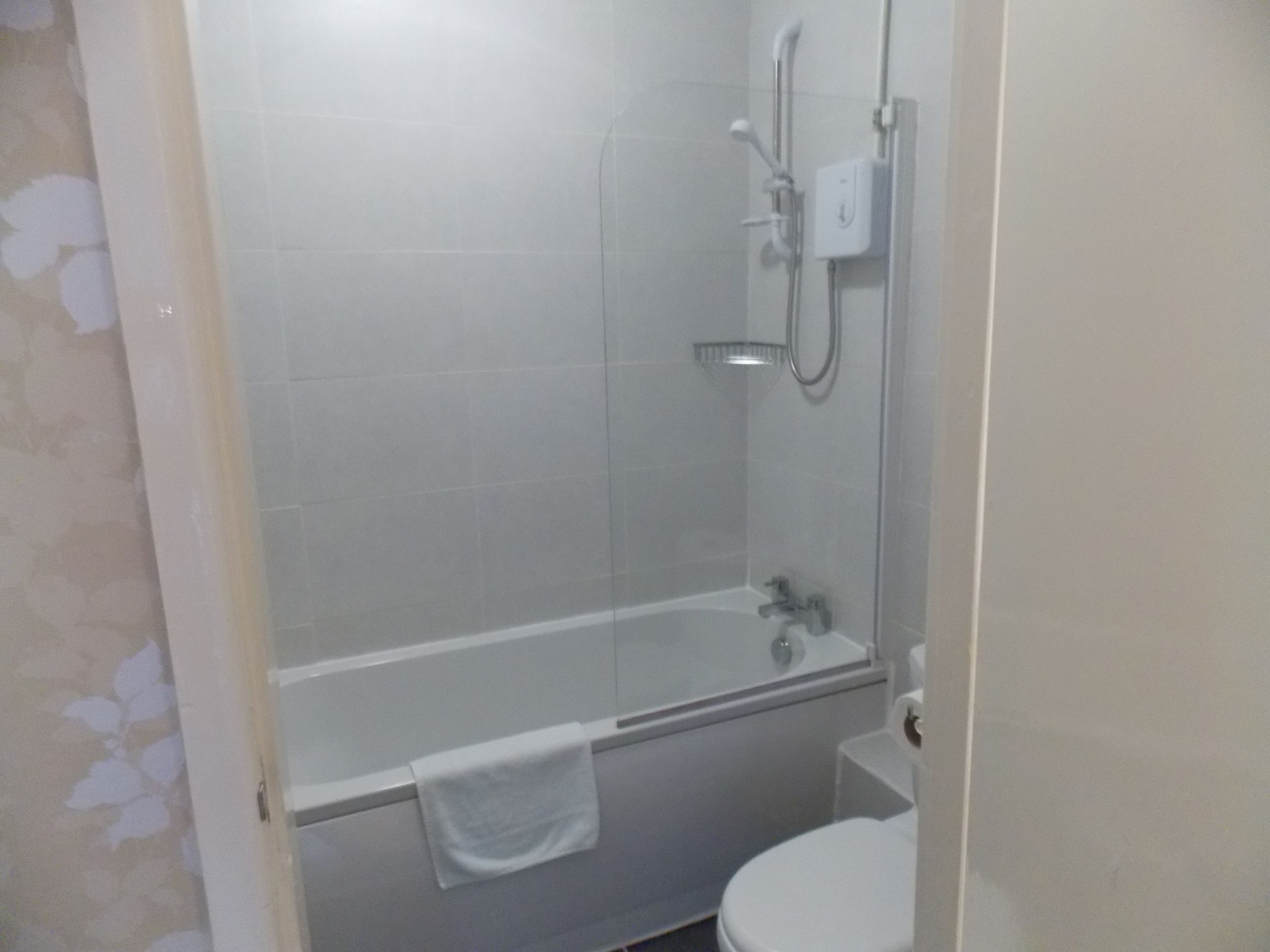 Un baño con ducha, bañera y retrete.
