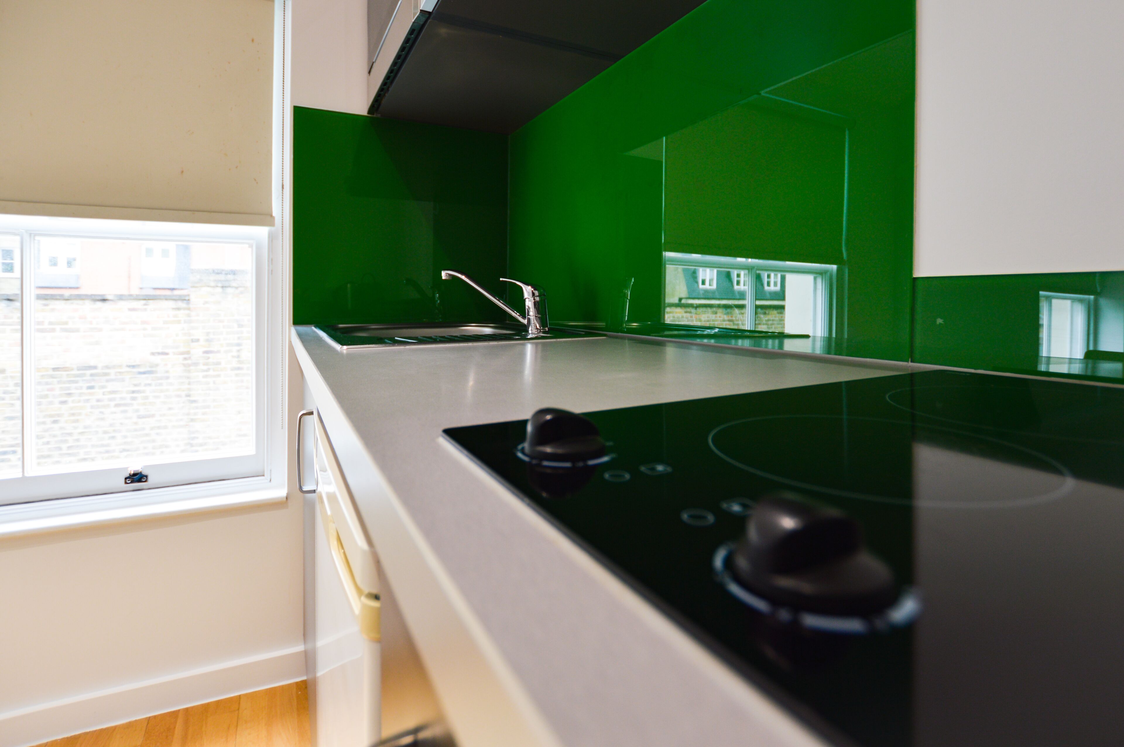 A kitchen with a green backsplash, a window, and a stove.