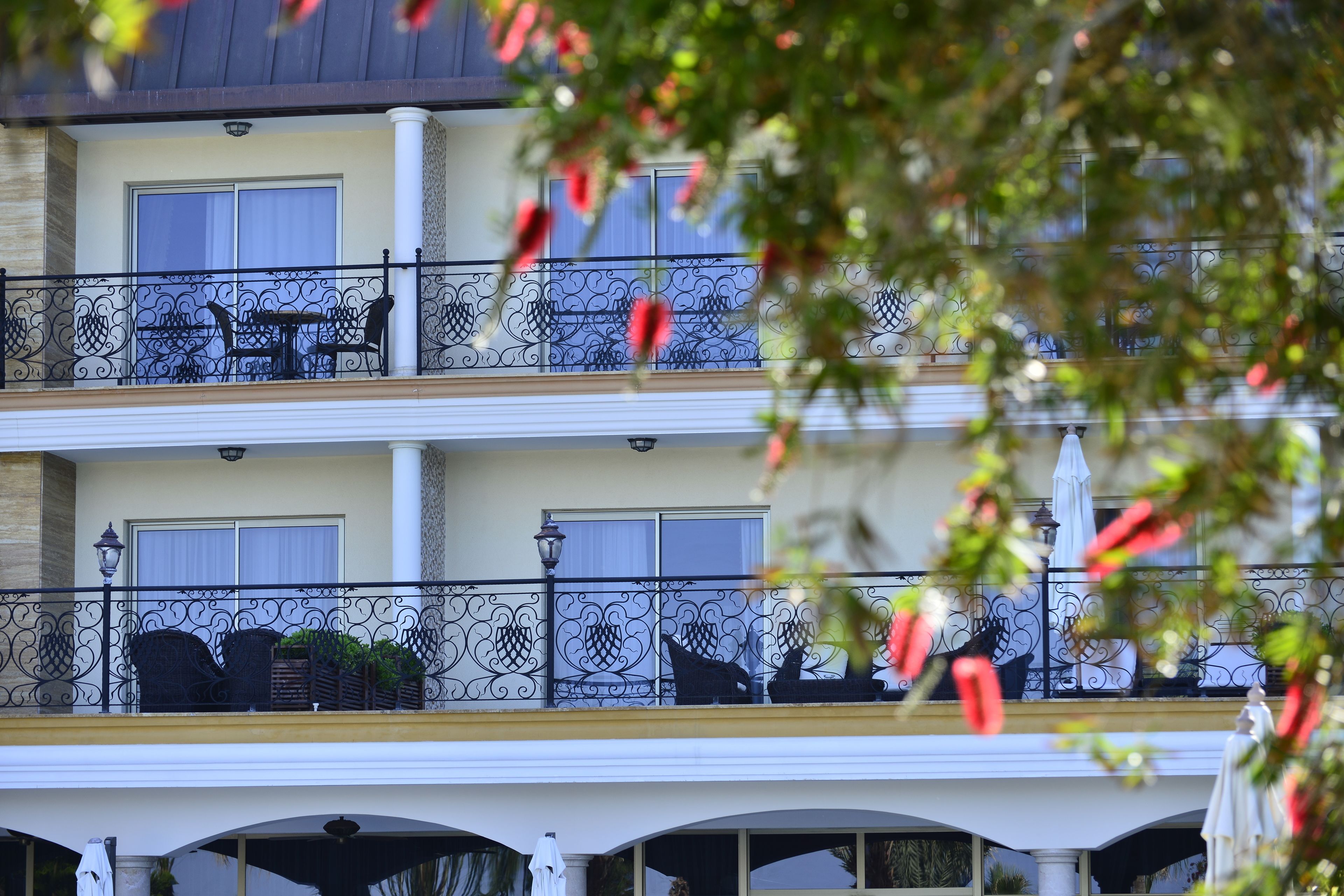 A hotel with a two-story balcony, outdoor seating, and decorative railings.