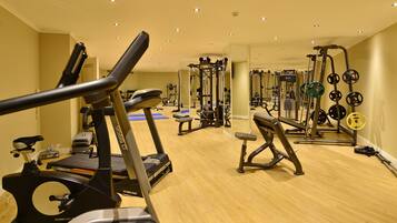 Un gimnasio con cintas de correr, máquinas de pesas y pesas libres.