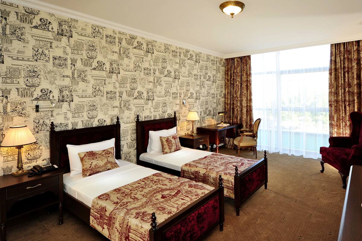Habitación de hotel con dos camas, un escritorio, una silla y una mesa de comedor con fruta.