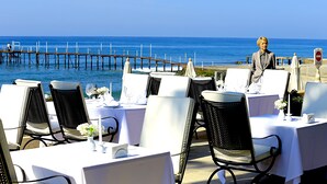 Een terras met eettafels voor twee personen, met uitzicht op de zee.