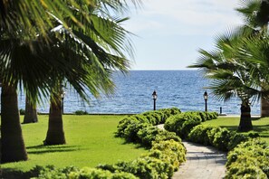 A pathway leading to a body of water, flanked by palm trees and well-maintained greenery. - Villa Augusto Boutique Hotel - Boutique Class (Alanya)