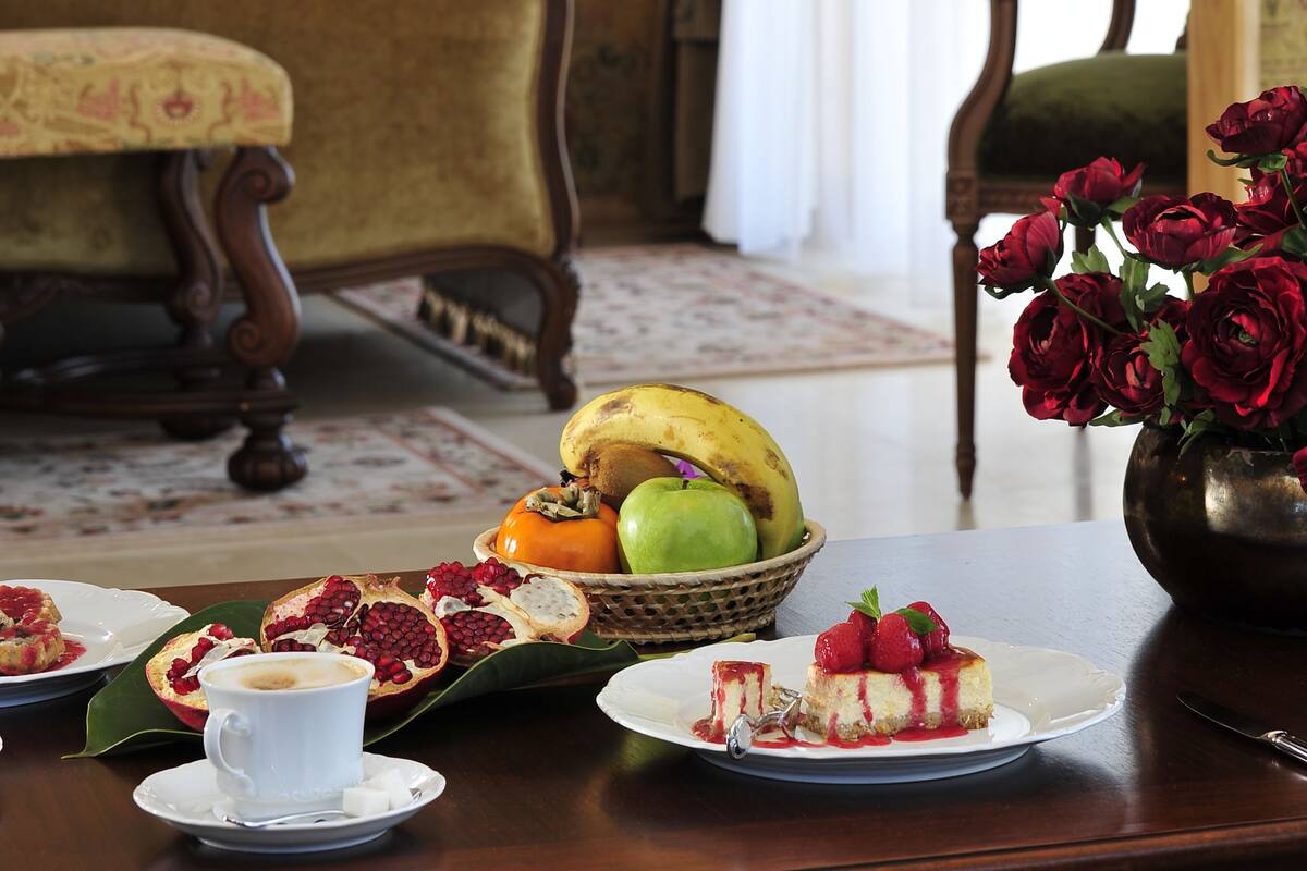 Una mesa de comedor con un plato de comida, una taza de café y un jarrón de flores.