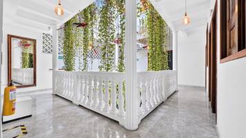 A hotel lobby with a white columned partition, hanging plants, and pendant lighting.