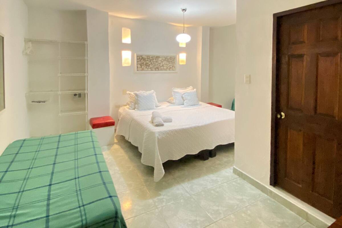 Un dormitorio con cama, mesita de noche, armario y una puerta.