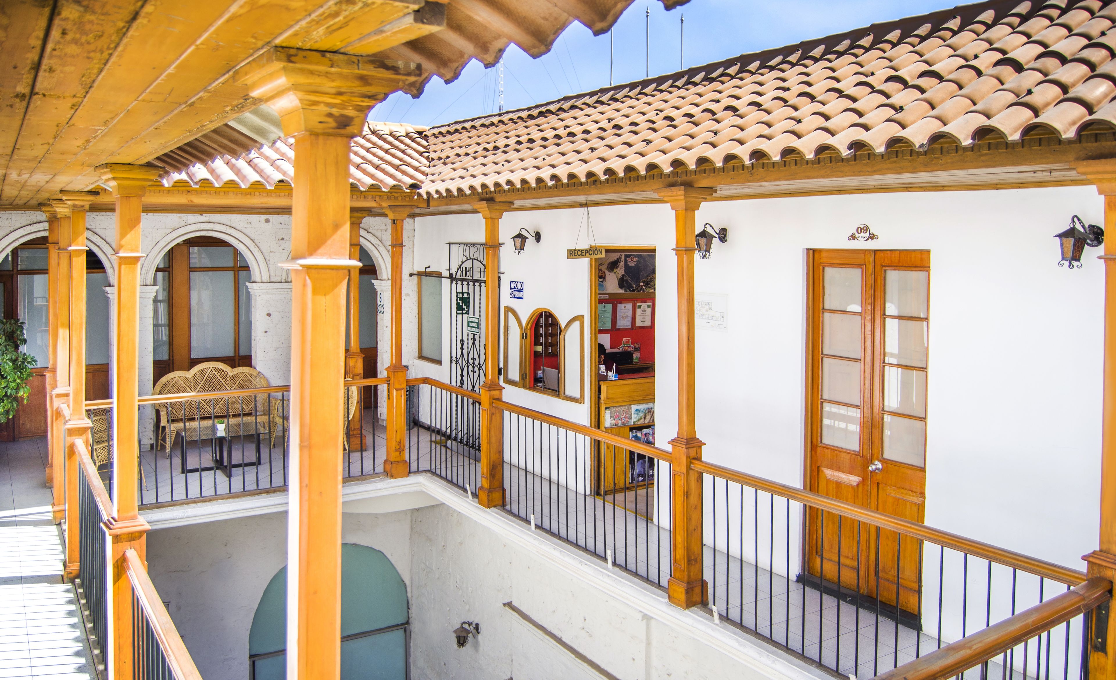 Un edificio tradicional con tejado de tejas, balcones de madera y una zona de recepción.