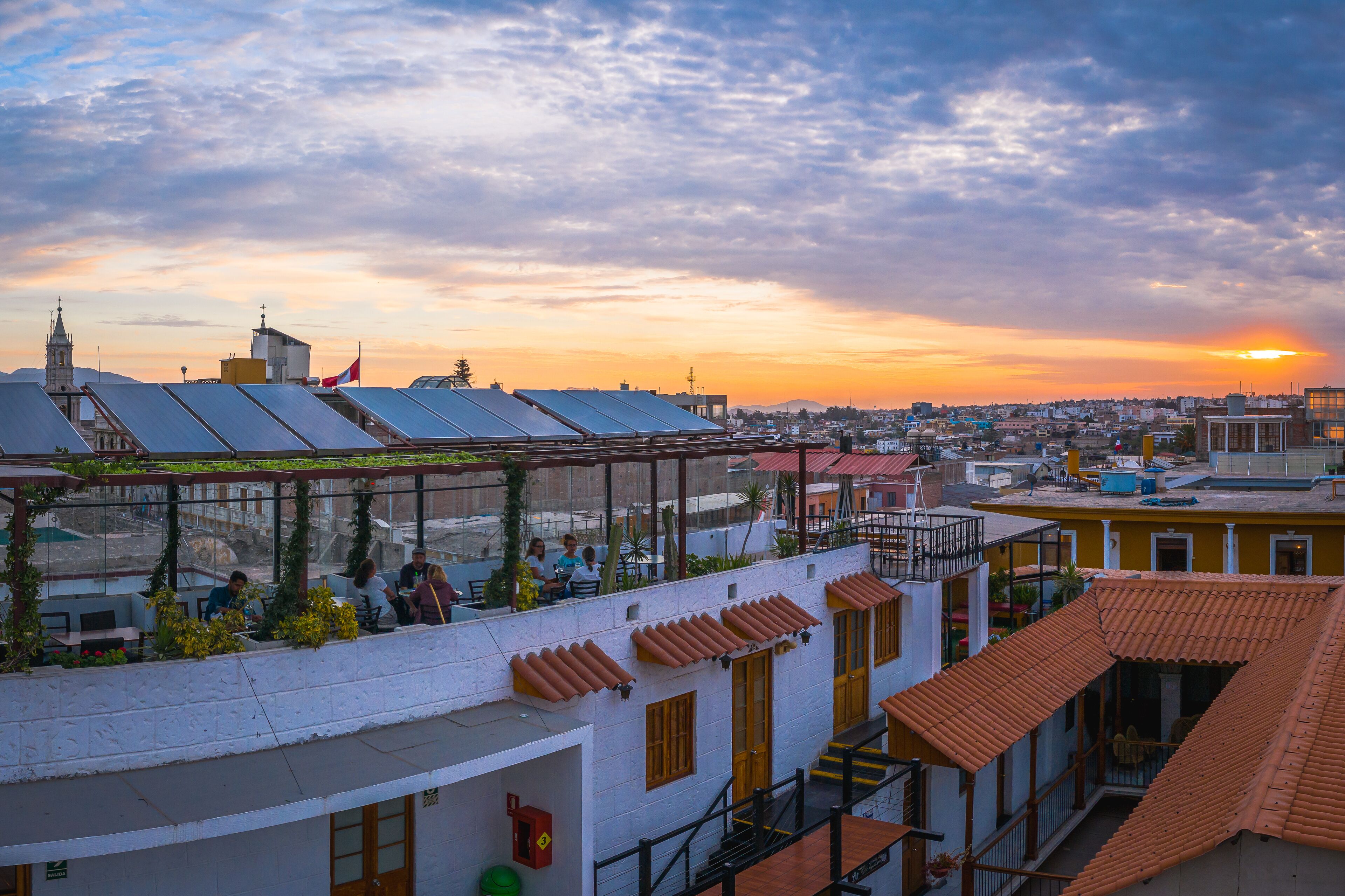 Terraza en la azotea con paneles solares, vistas de la ciudad y un atardecer.