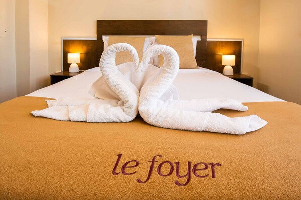 Une chambre d’hôtel avec un lit, deux tables de chevet et une décoration artistique réalisée avec des serviettes, disposée sur le lit.
