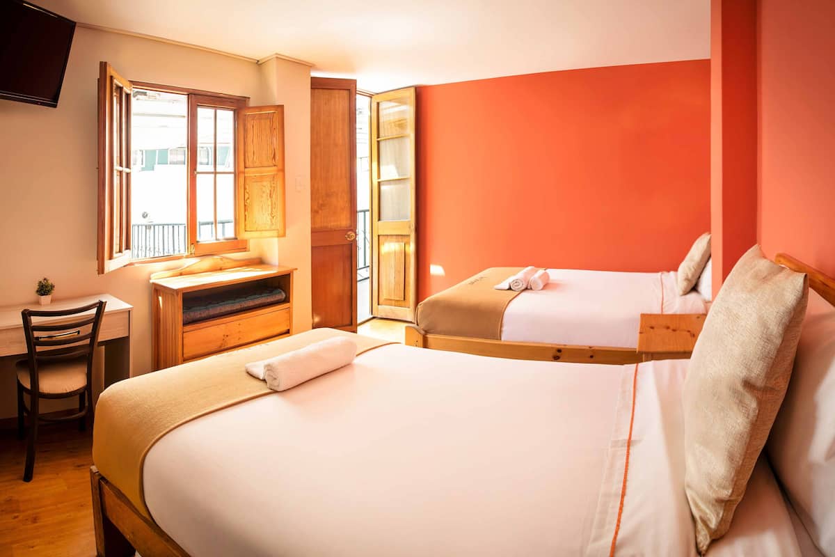A hotel room with two beds, a desk, and a chair.