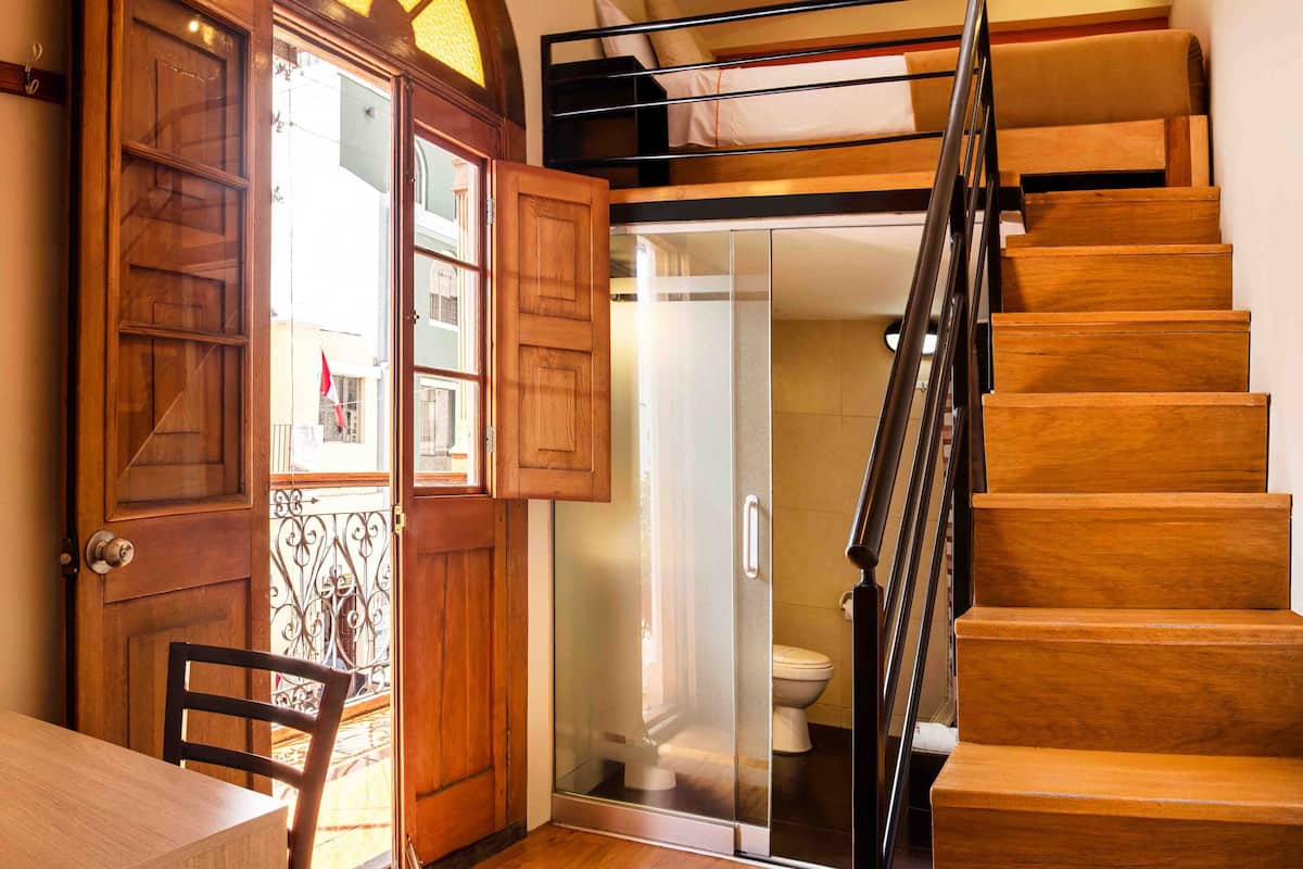 A wooden staircase leading to a second floor, a glass door entrance, and a dining area with a table and chair.