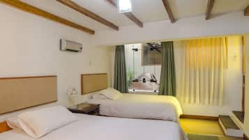 A hotel room with two beds, a nightstand, a lamp, a ceiling fan, and a window with curtains.