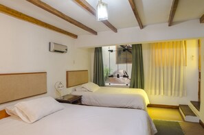 A hotel room with two beds, a nightstand, a lamp, a ceiling fan, and a window with curtains. - Los Áticos (Cusco)
