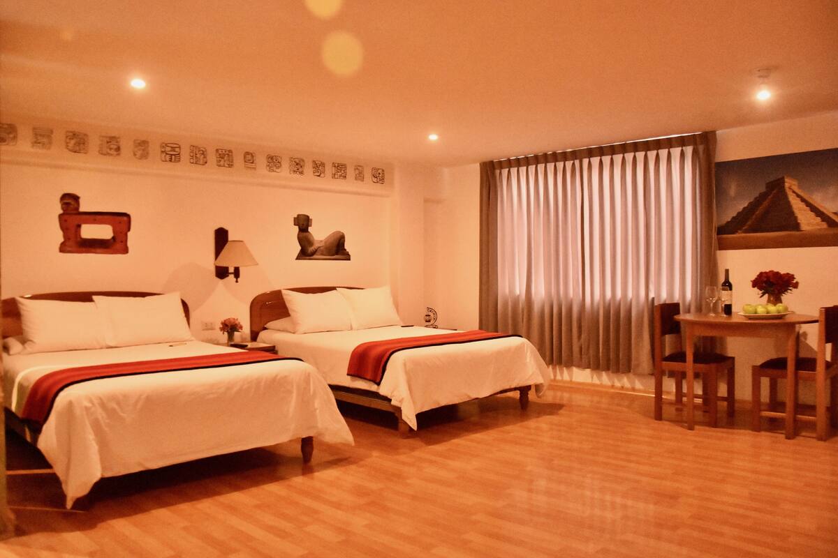 A hotel room with two beds, a dining table, and a mural on the wall.