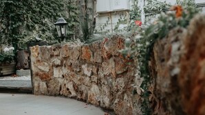 A stone wall with a lantern, surrounded by greenery and a tiled floor. - Hotel Crystal Reims Centre (Reims)