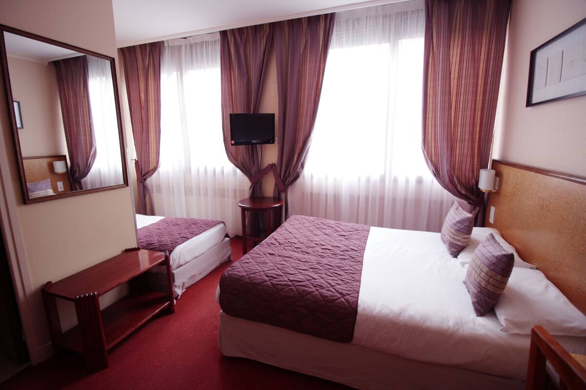 Een hotelkamer met twee bedden, een televisie, een bureau en een spiegel.