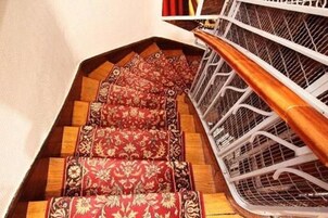 Eine Treppe mit Holzbodenstufen und einem roten Teppich mit Muster.