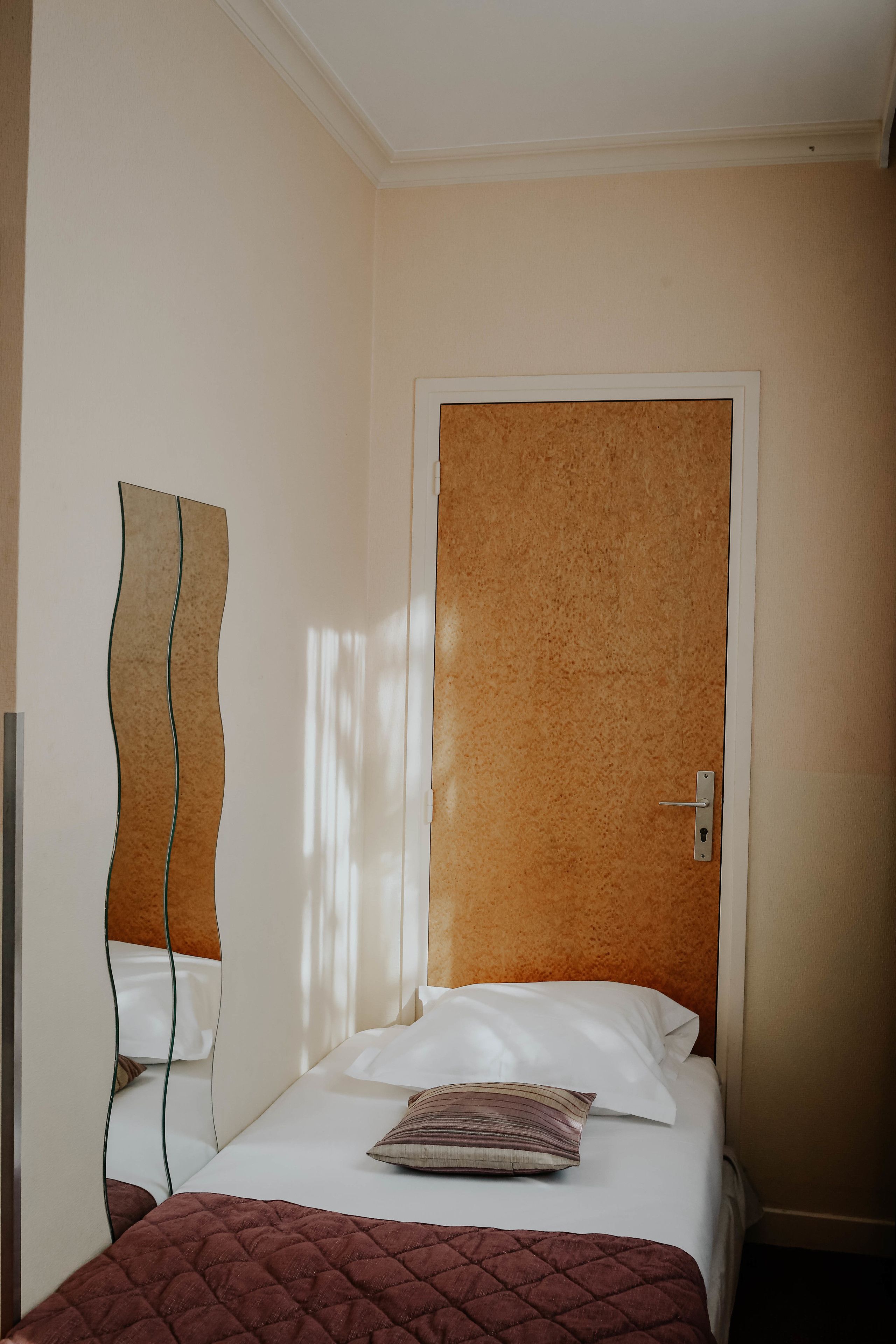 Ein Hotelzimmer mit einem Bett, einer Tür und einem an der Wand befestigten Kunstwerk.