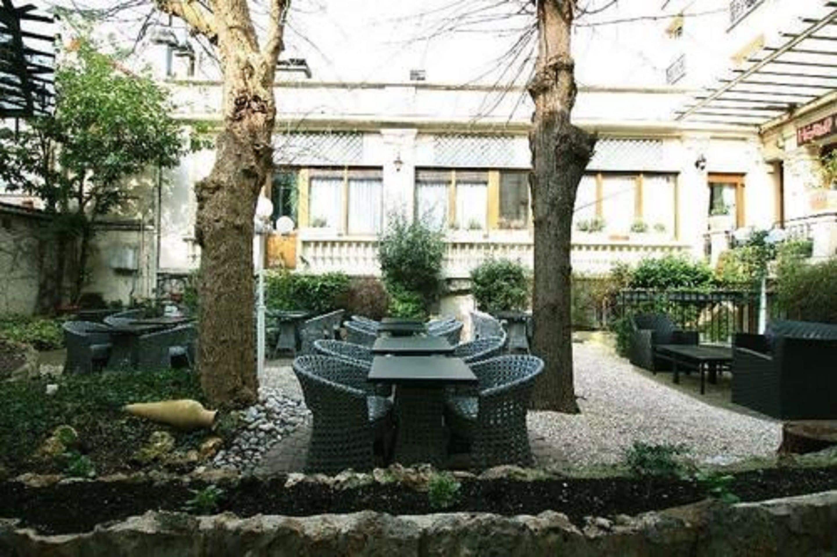Un patio al aire libre con una mesa redonda y sillas, rodeado de árboles y un sendero de grava.