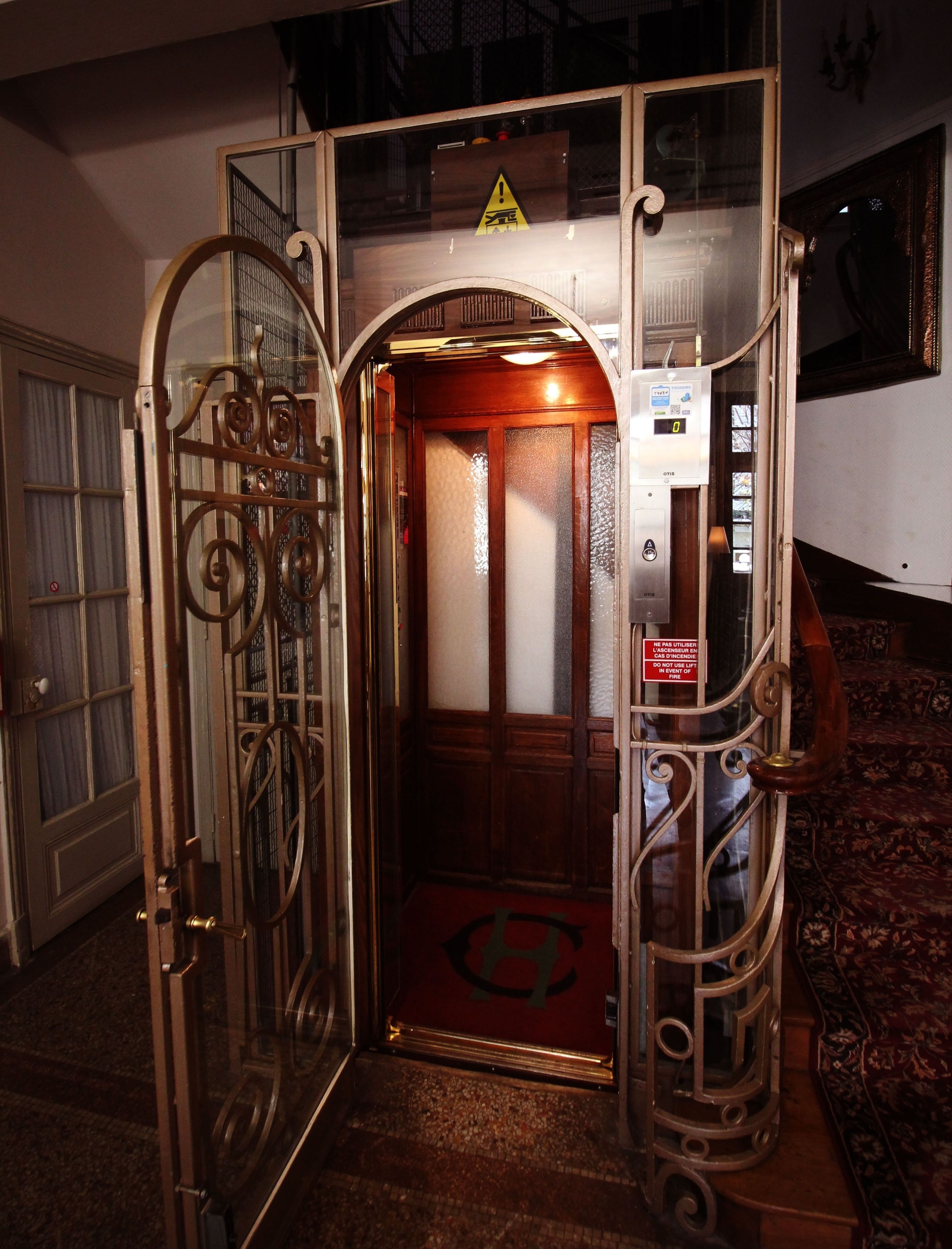 Un ascensor con barandillas de metal ornamentadas y un letrero de advertencia.