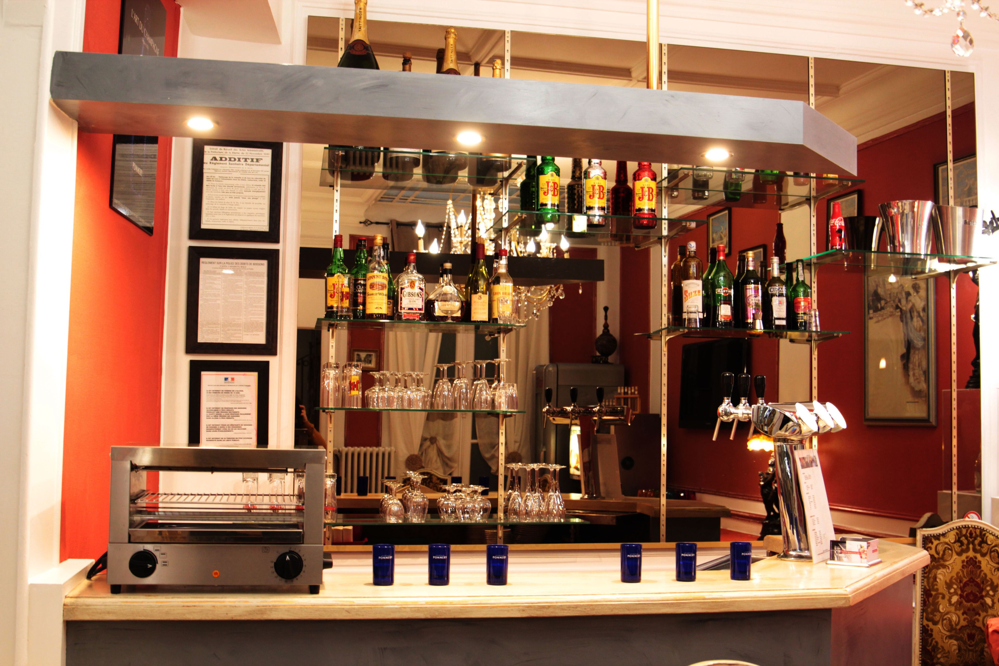 Angolo bar con scaffali pieni di bottiglie di liquori, bicchieri e una macchina da caffè.