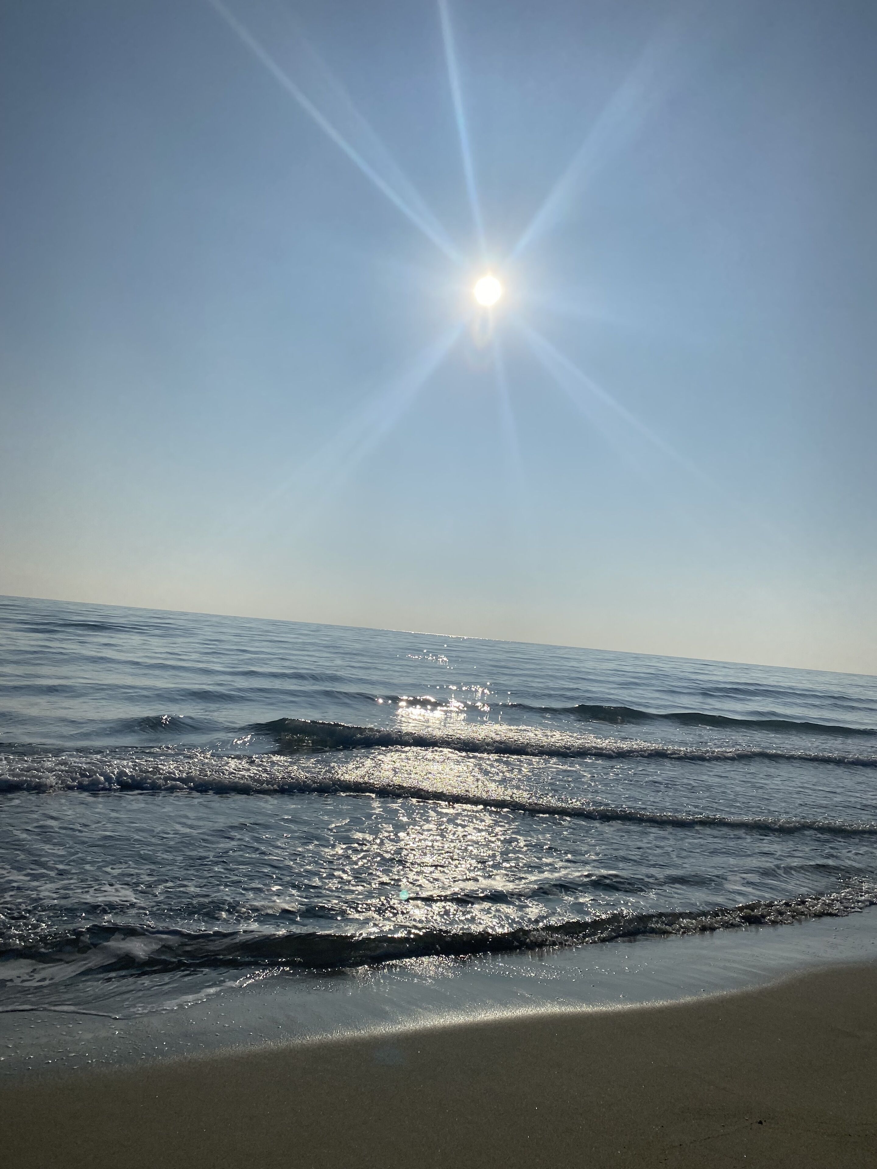 A beach with waves and sunlight reflecting on the water.