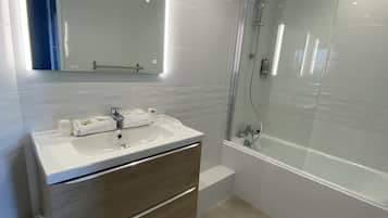 A modern bathroom with a vanity, sink, mirror, and shower area.
