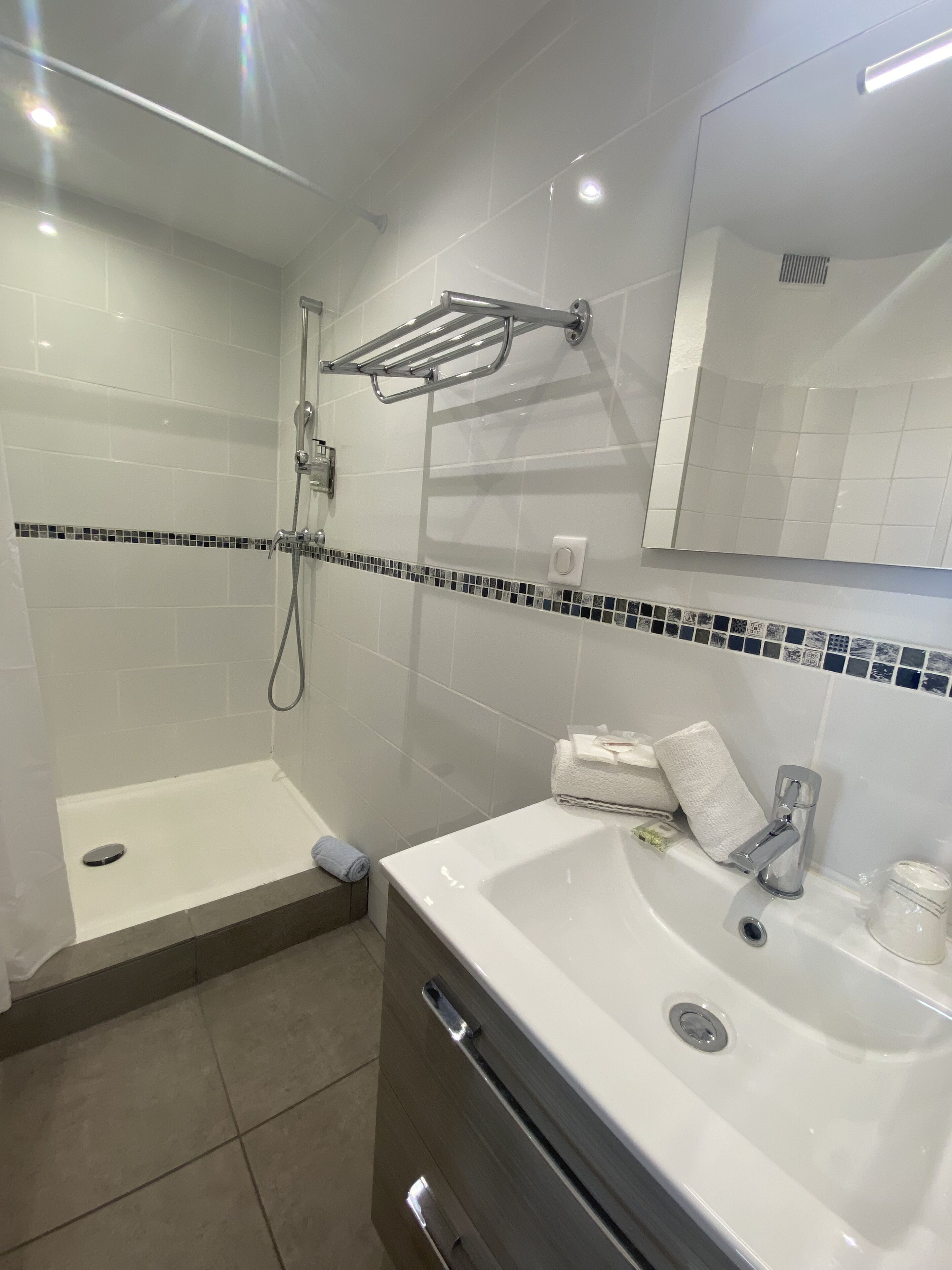 Une salle de bain moderne équipée d’une douche, d’un lavabo et d’un miroir.