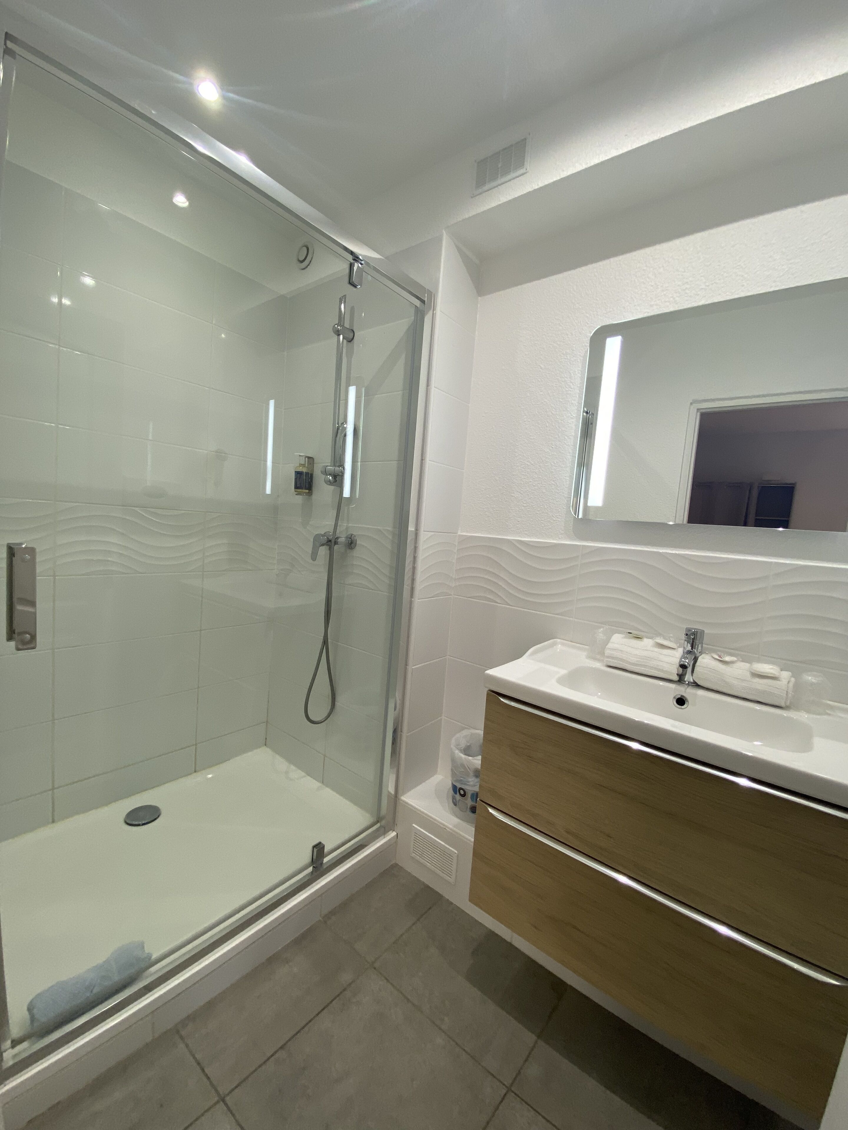Une salle de bain moderne avec une douche à parois de verre, un meuble-lavabo avec un miroir et un évier.