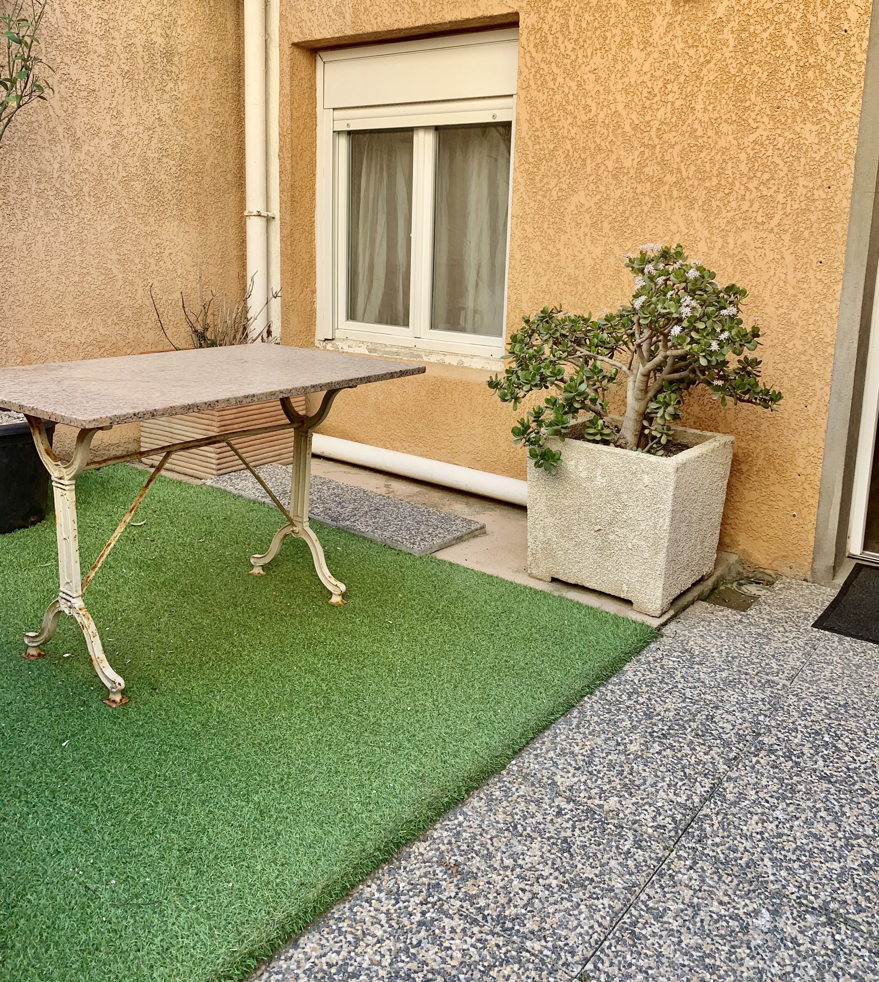 Een terras met een tafel en een bloempot.