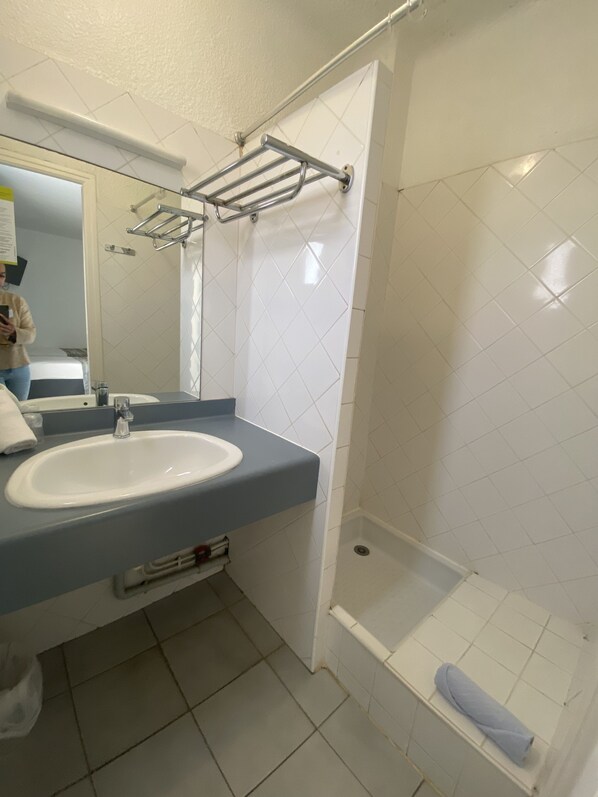 A bathroom with a sink, mirror, and shower.