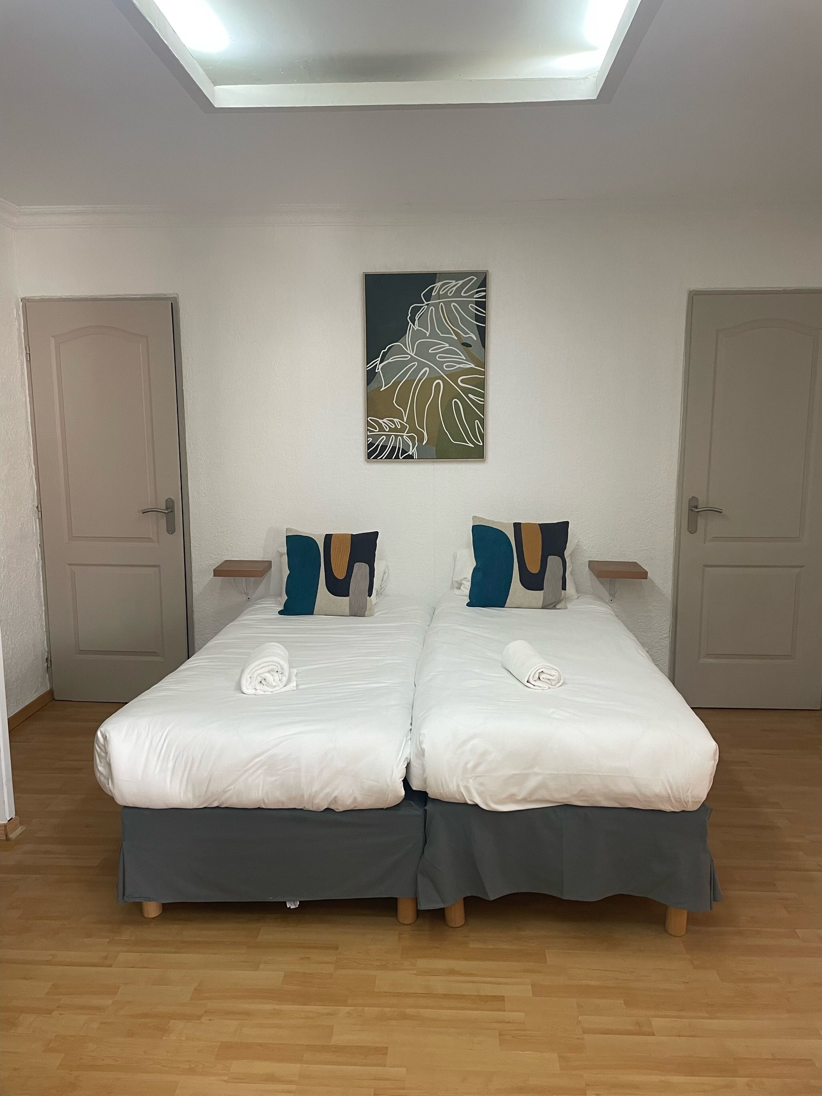 A twin room with two beds, a ceiling light, and a wall art piece.
