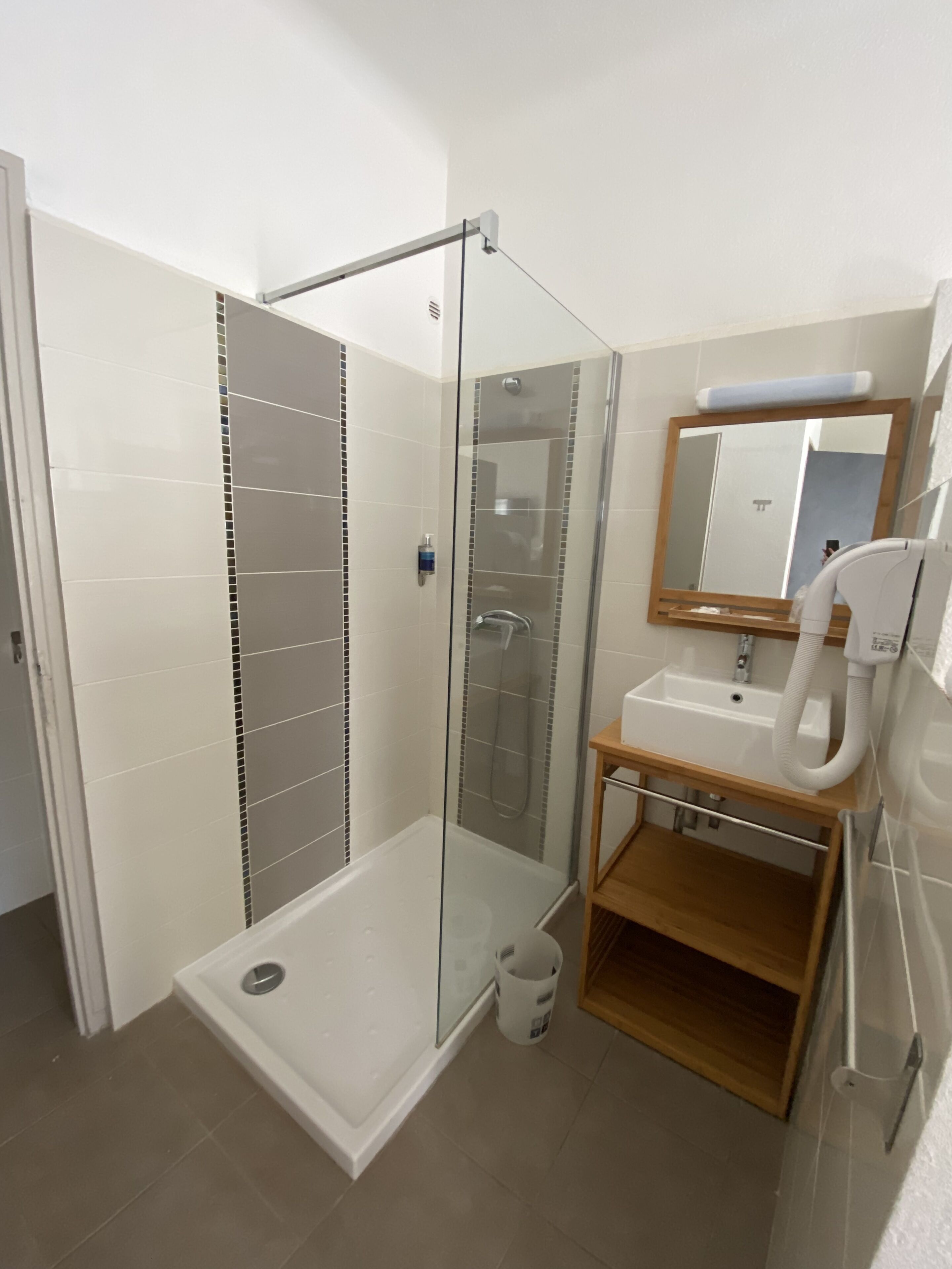 Un baño moderno con ducha de vidrio, lavabo con espejo y un mueble de madera.