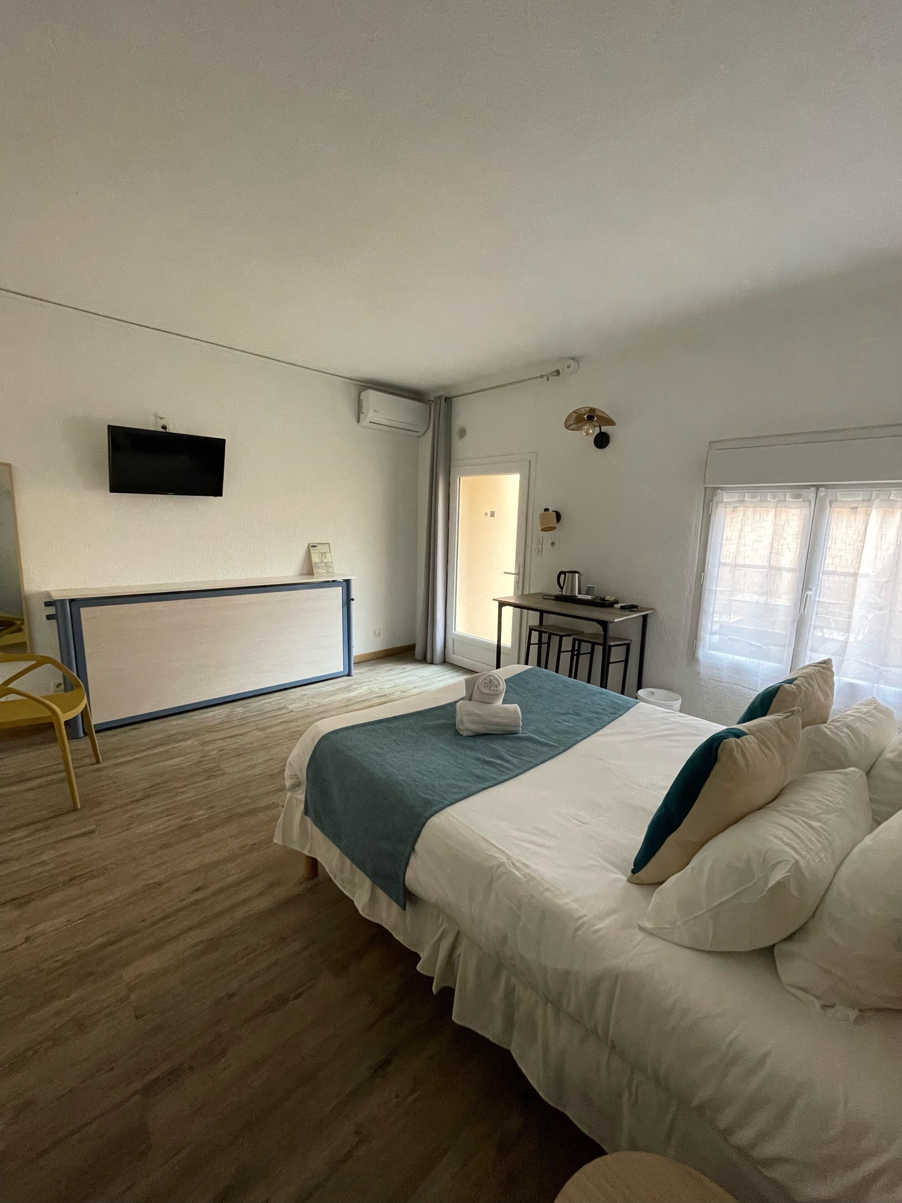 Une chambre d’hôtel avec un lit, un bureau, une chaise, une télévision et une fenêtre.