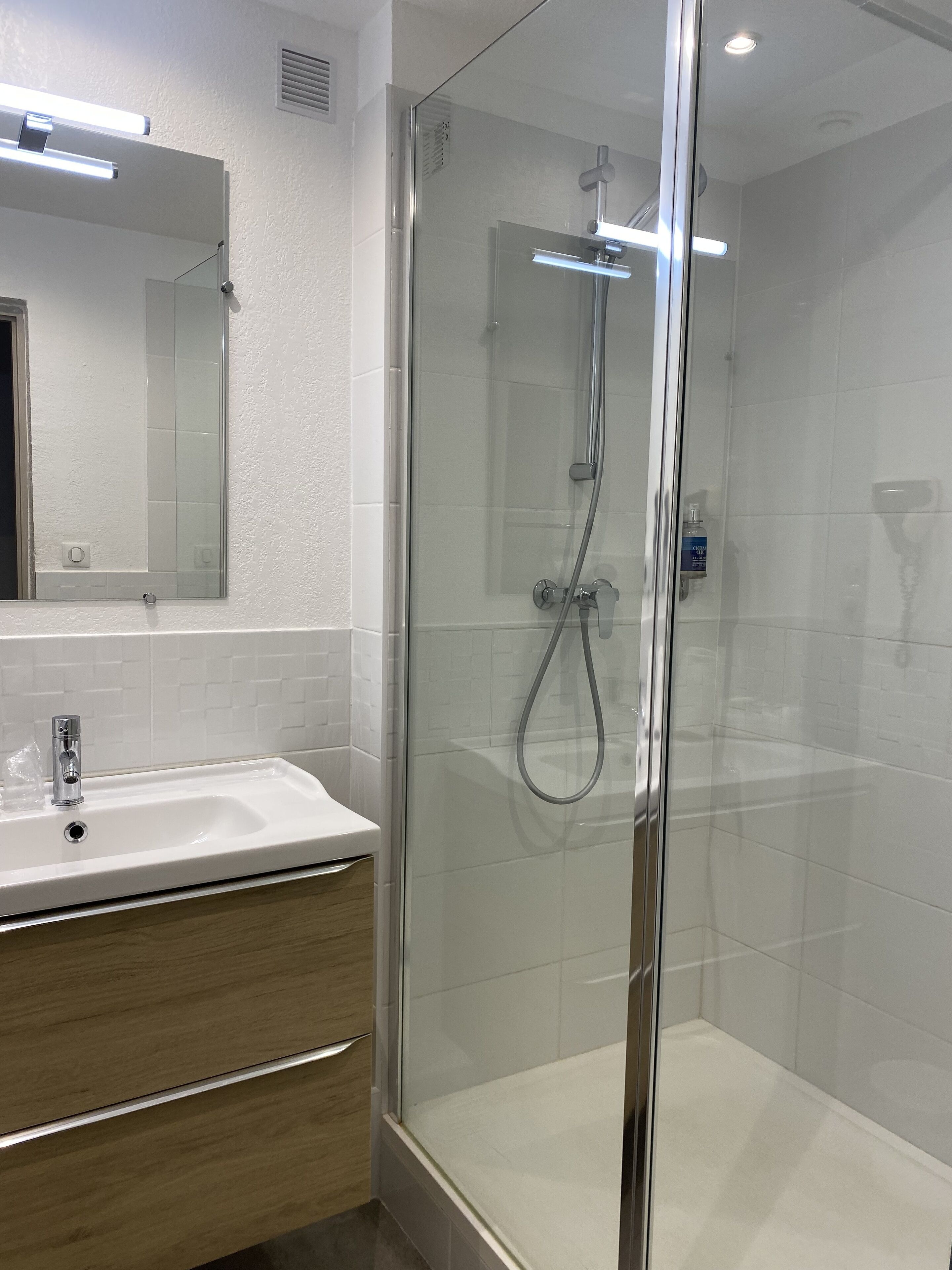 A modern bathroom with a glass-enclosed shower, a white sink, and a mirror above the sink.