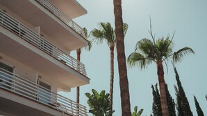 Un edificio de varios pisos con balcones y palmeras.