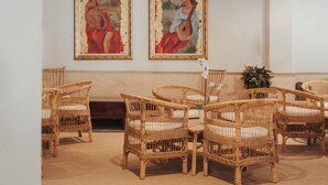 Una habitación con muebles de mimbre, dos cuadros en la pared y una planta en maceta.