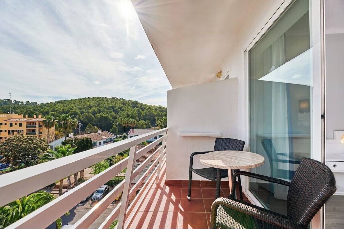 A balcony with a white railing, a small round table, and two wicker chairs.