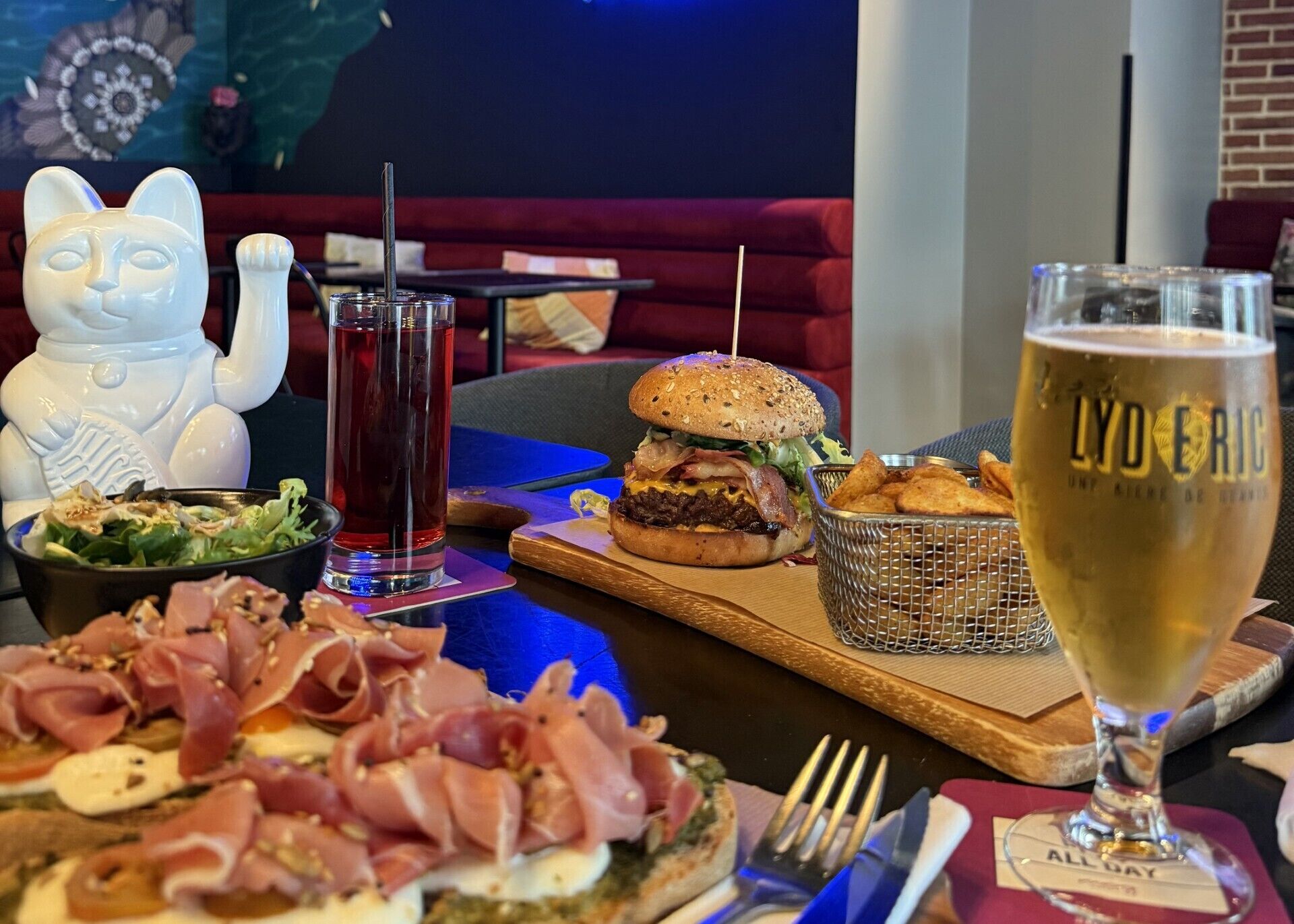 A dining table with a variety of food items, a glass of beer, and a decorative ceramic figure.